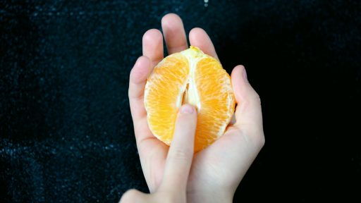 person holding sliced orange fruit