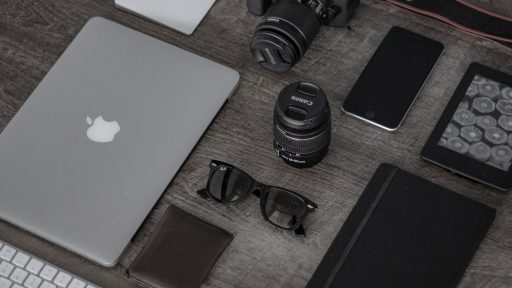 iPad near sunglasses, wallet, and DSLR camera