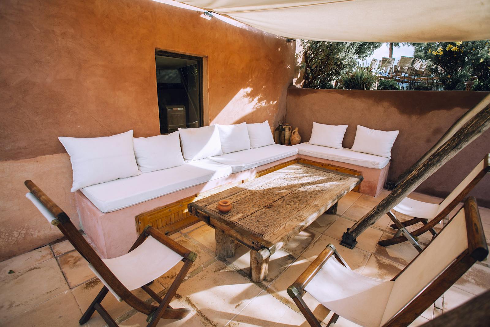 Inviting outdoor patio with rustic wooden furniture and white cushions, perfect for relaxation.