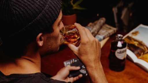 man in black knit cap holding clear glass mug