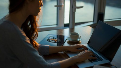 woman sitting beside table using laptop