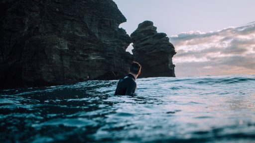 Man op het strand in een zwemshort bij helder blauw water