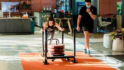 Man die een zware sled duwt in een sporthal tijdens een Hyrox-training