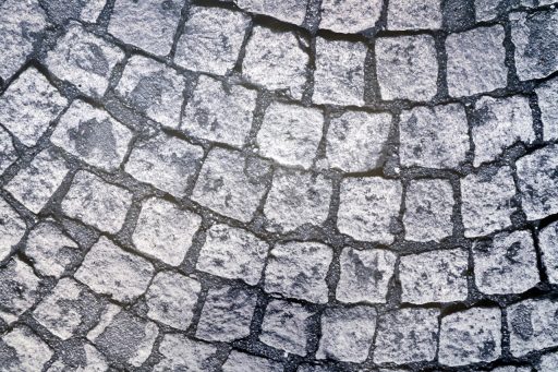 Man die klinkers legt op een oprit met een africhtlat en zandbed