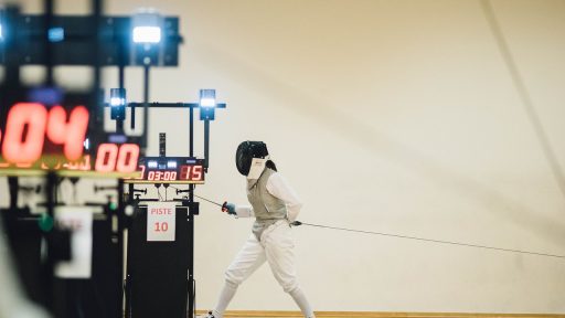 Twee schermers in gevecht op de piste met maskers en degens