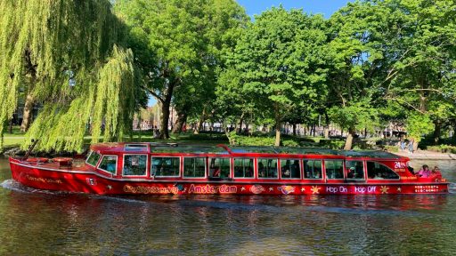 red passenger boat beside green leafed trees
