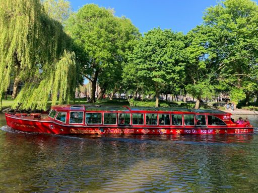 red passenger boat beside green leafed trees