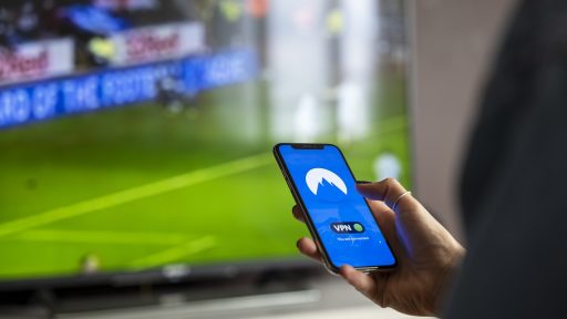 Man bekijkt beleggingsapp op zijn telefoon terwijl hij koffie drinkt