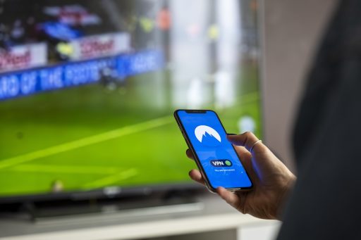 Man bekijkt beleggingsapp op zijn telefoon terwijl hij koffie drinkt