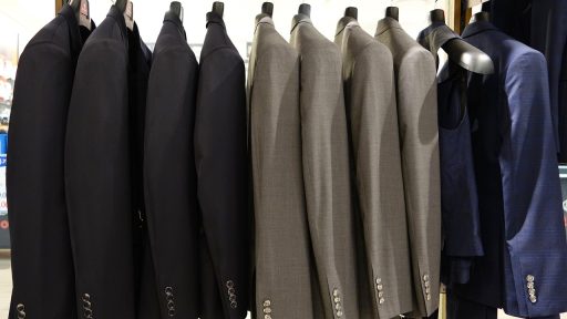 Interieur van een herenkledingwinkel met nette jassen en overhemden op rekken