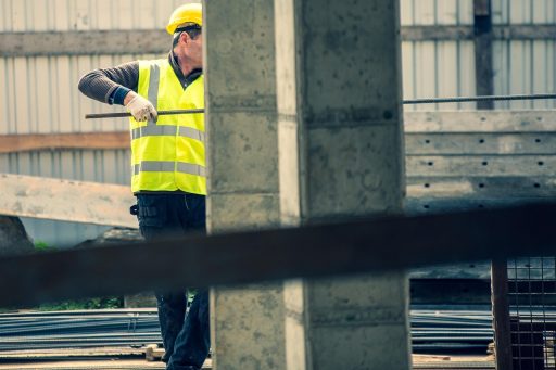 Een bouwvakker in stevige werkkleding buiten op een bouwplaats bij bewolkt weer