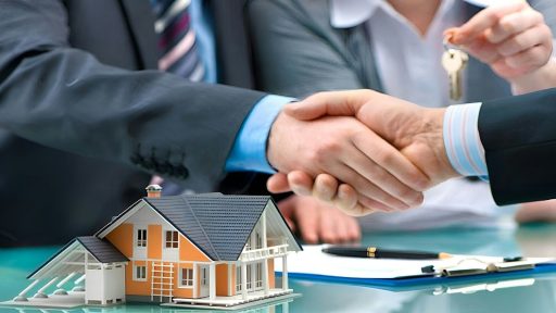 Two men shaking hands over a house model and keys