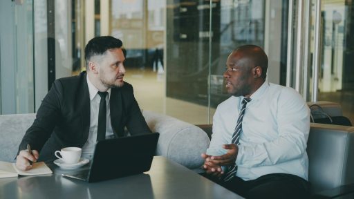 Two businessmen in suits talking in a modern office