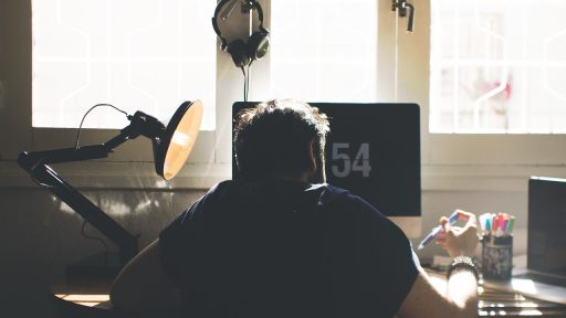 Man aan bureau met lichttherapielamp naast zijn beeldscherm tijdens het werken