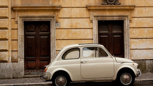 white volkswagen beetle parked beside brown brick building during daytime